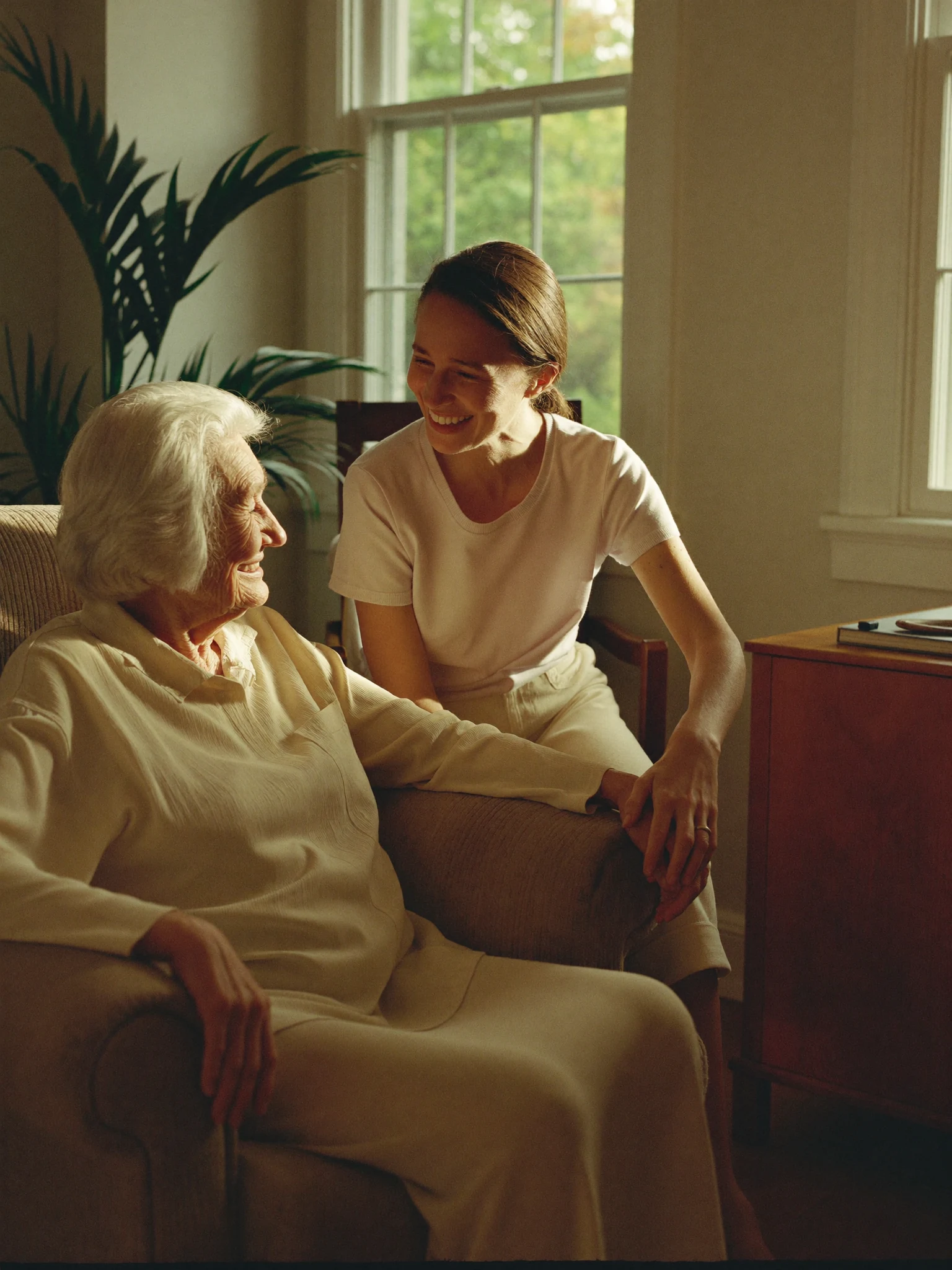 An older woman and her adult daughter sharing a quiet moment at home. Illustrative AI-generated photograph.